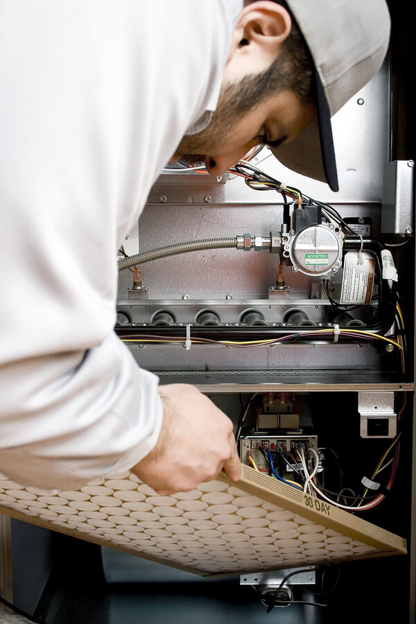 HVAC technician replacing filter on furnace