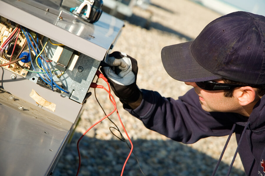 Worker testing a roof top air exchange units operation.